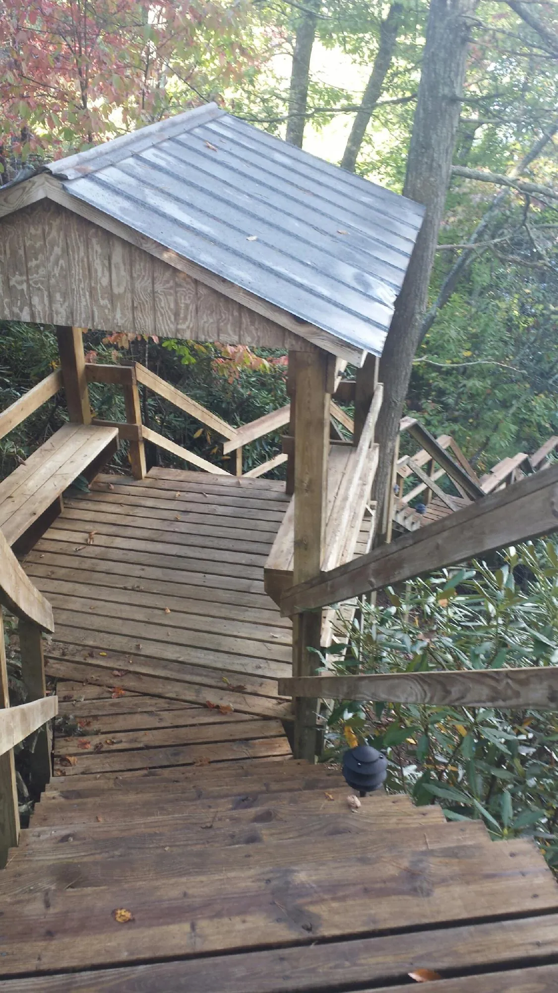 Metal roofed shelter over wooden steps on a wooded walkway — Skylight Repair & Installation work by our crew in Monticello