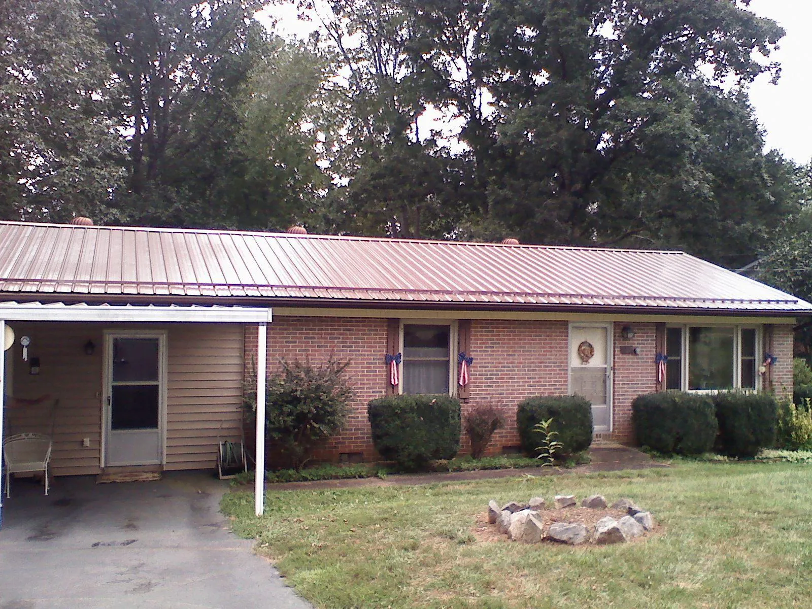 Bronze metal roof and carport on a brick ranch home — Roof Repair work by our crew in Monticello